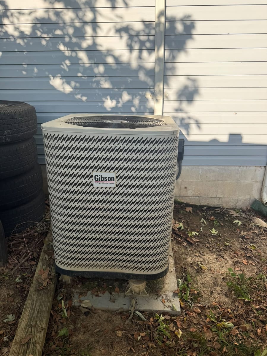 Outdoor condenser set level on blocks beside blue siding