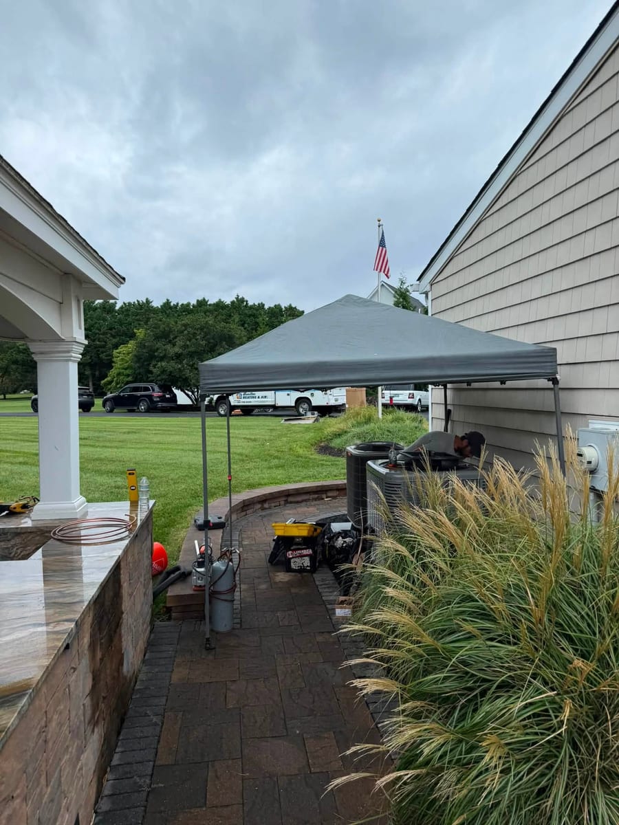 Outdoor job site with a canopy tent, equipment and a paved patio