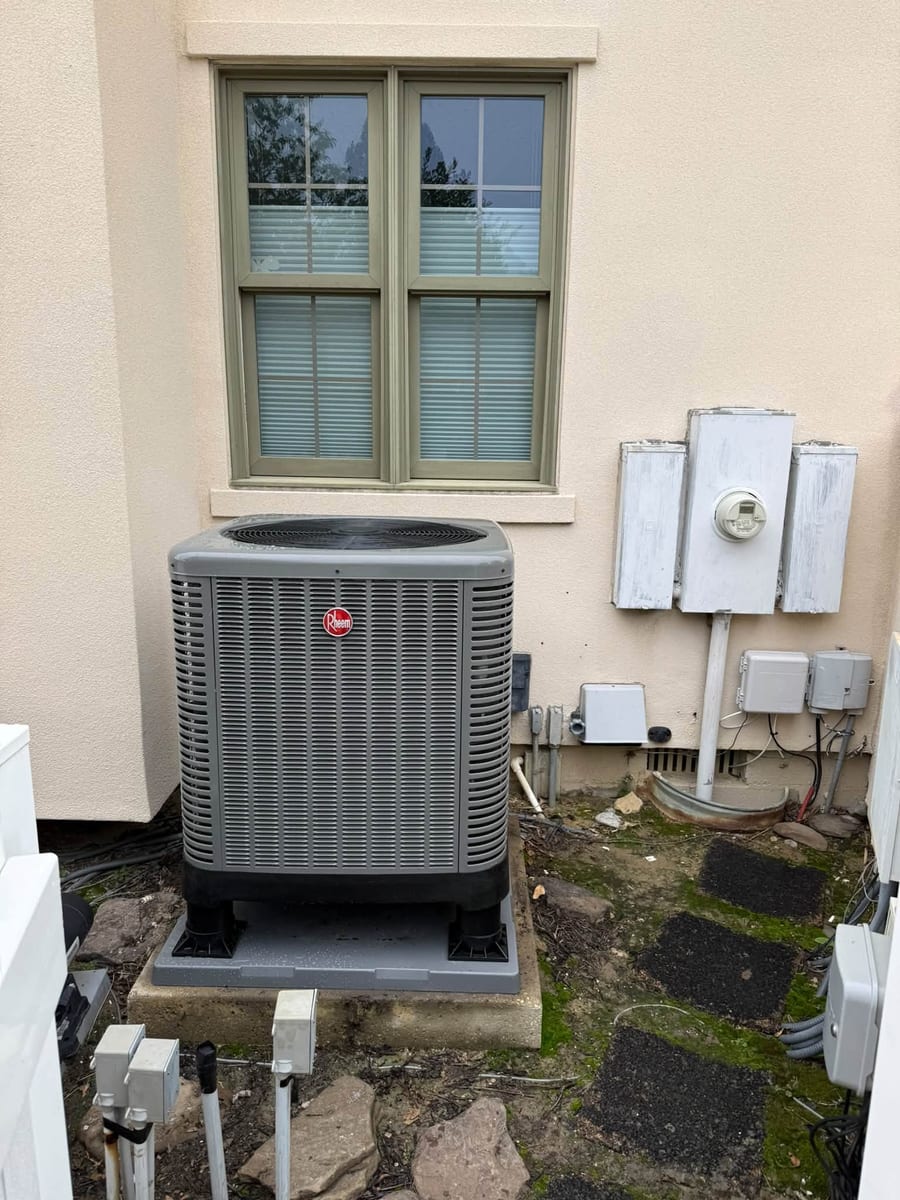 New outdoor unit on a pad beside a stucco wall and electric meters