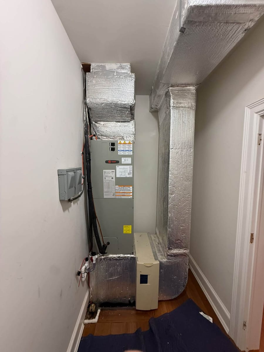 Air handler and foil wrapped ductwork in a hallway utility closet